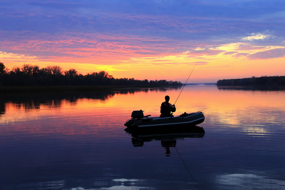 黄昏平静湖面上钓鱼的人物高清图片素材